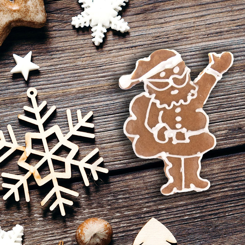 Galletas de Navidad con forma de Papá Noel y copos de nieve sobre madera.