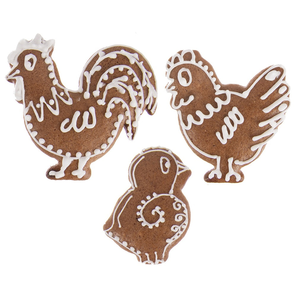 Tres galletas de jengibre: gallo, gallina y pollito, decoradas con glaseado blanco.