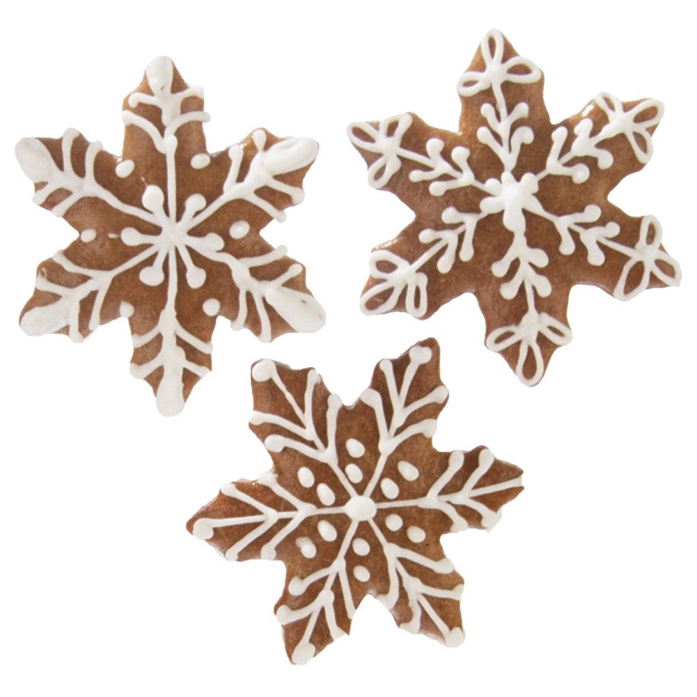 Tres galletas de jengibre marrones en forma de copo de nieve decoradas.