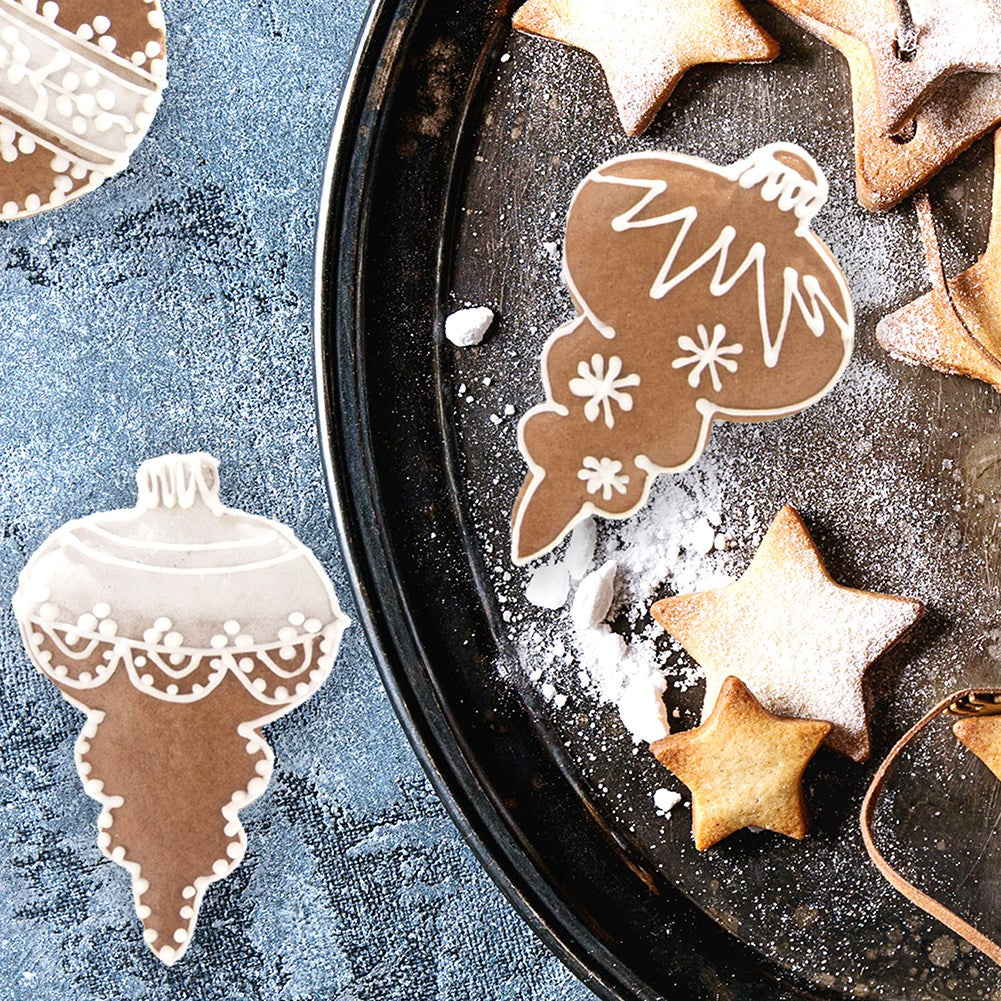 Galletas de jengibre con forma de adornos navideños y estrellas en una bandeja.