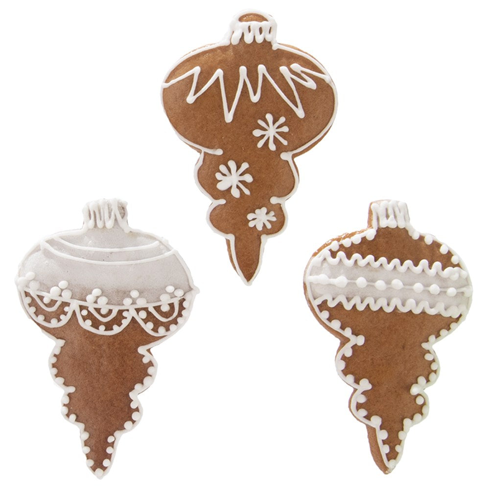 Tres adornos navideños de pan de jengibre con forma de bolas decorados con glaseado blanco.