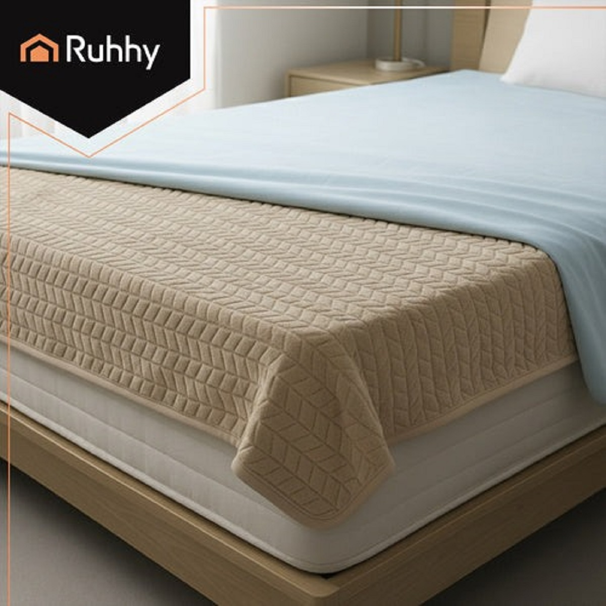 Una manta beige acolchada cubre un colchón, con una sábana azul encima.