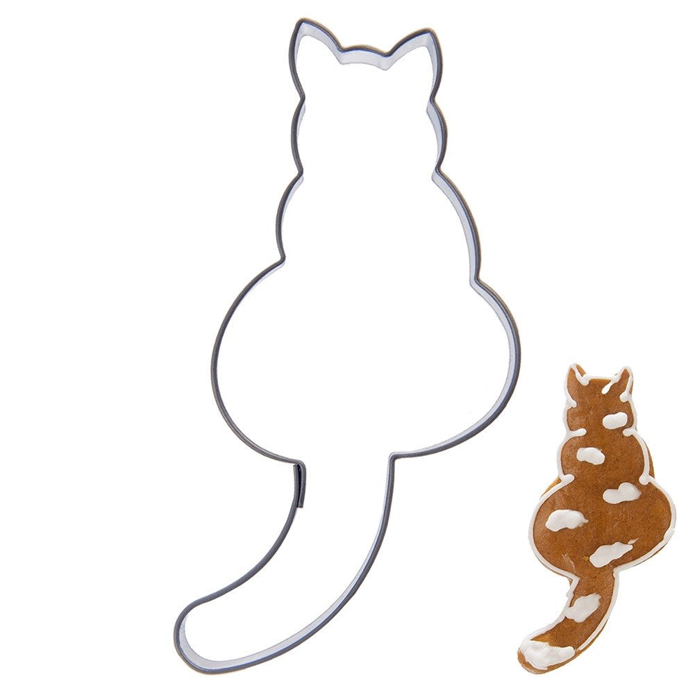 Un cortador de galletas con forma de gato y una galleta decorada al lado.