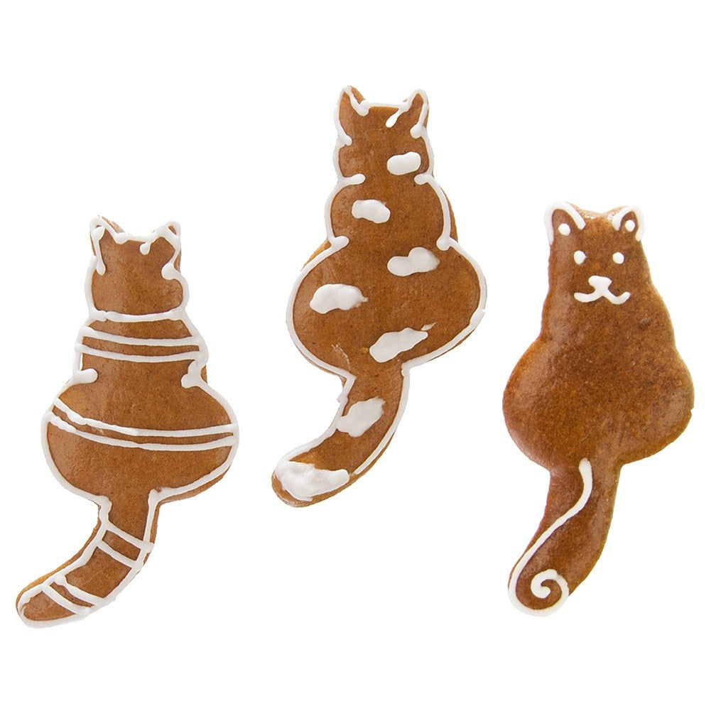 Tres galletas marrones con forma de gato decoradas con glaseado blanco.