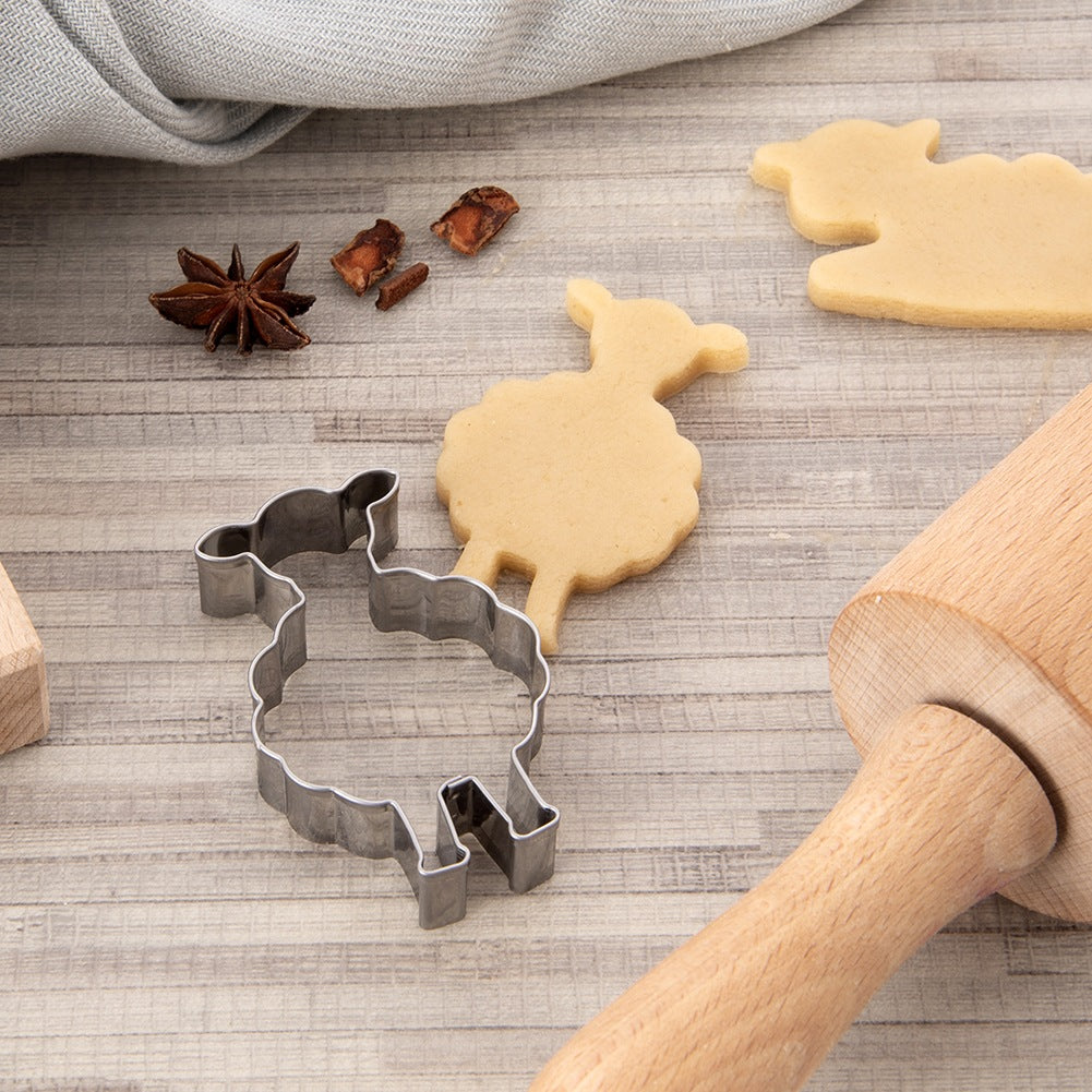 Un cortador de galletas de oveja y galletas sobre fondo de madera.