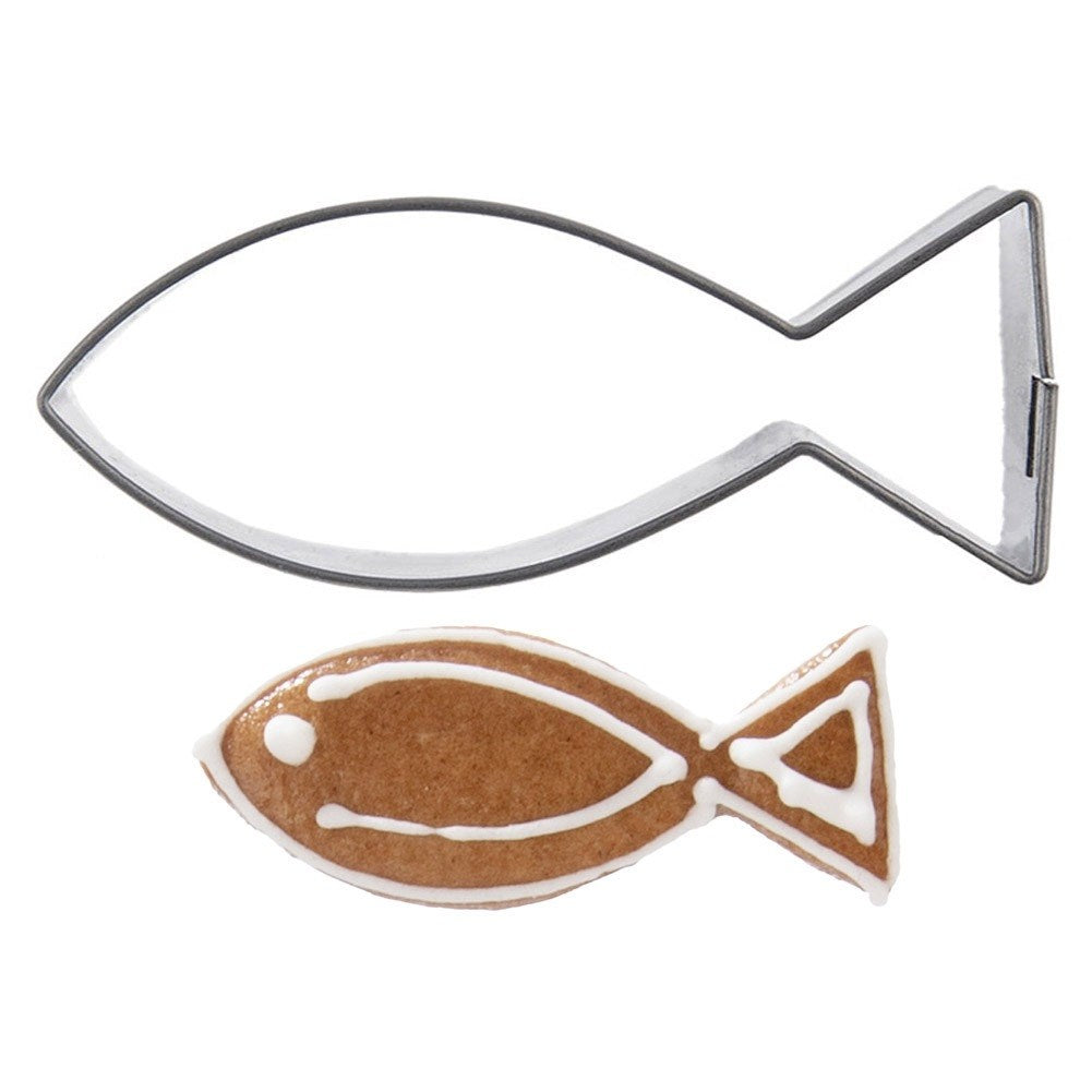 Un cortador de galletas de metal con forma de pez y una galleta con glaseado.