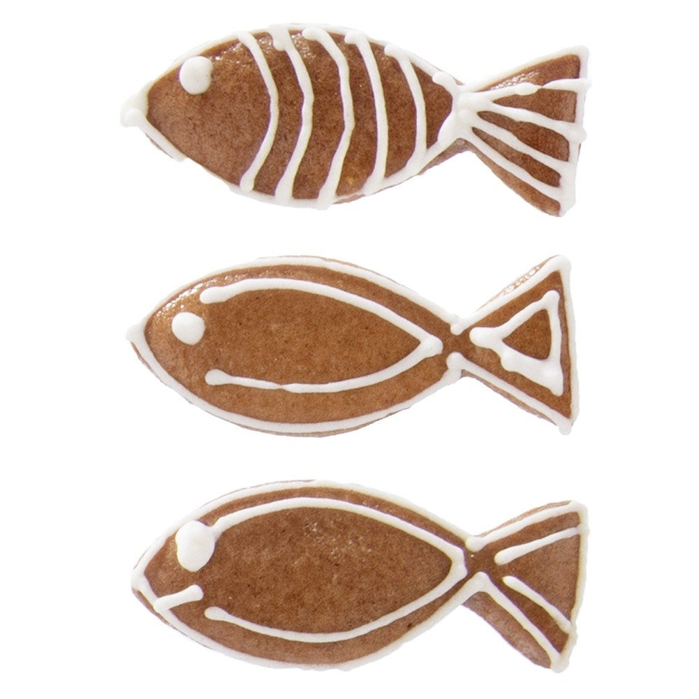 Tres galletas marrones con forma de pez decoradas con rayas y puntos de glaseado blanco.
