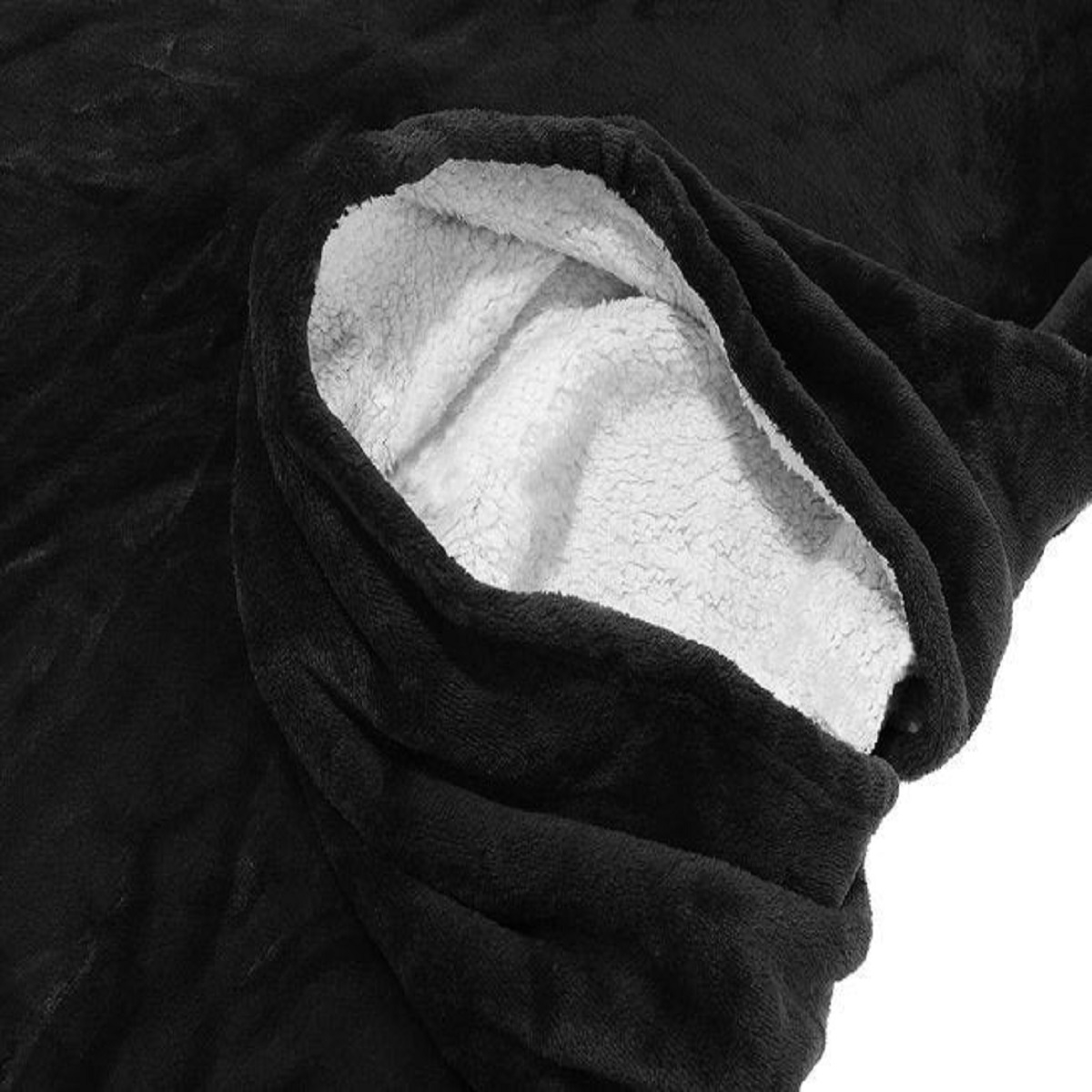 Manta sherpa negra con forro de oso de peluche blanco, primer plano.