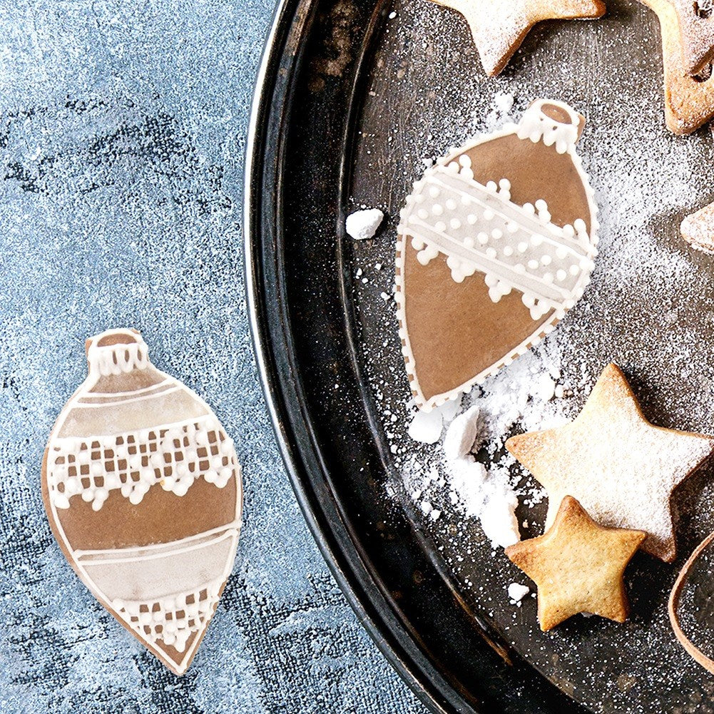 Galletas navideñas marrones con forma de adornos y estrellas en una bandeja.
