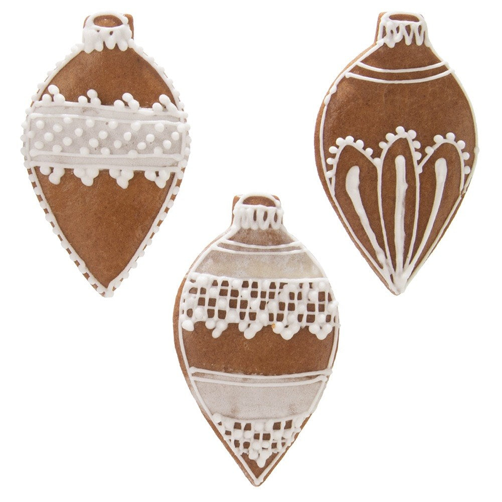 Tres adornos navideños de pan de jengibre marrones decorados con glaseado blanco.