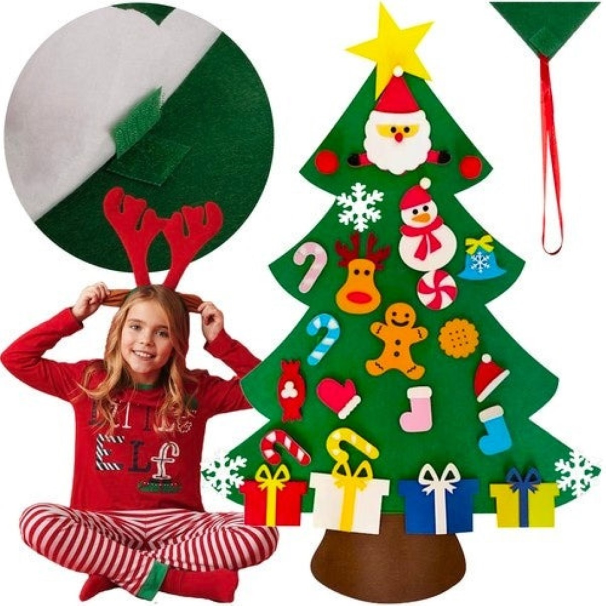 Una niña con astas de reno se sienta ante un árbol de Navidad de fieltro verde con decoraciones.