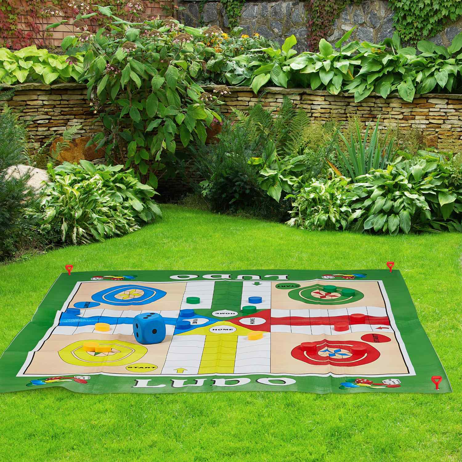 Gran juego de Ludo sobre césped con dados y fichas.