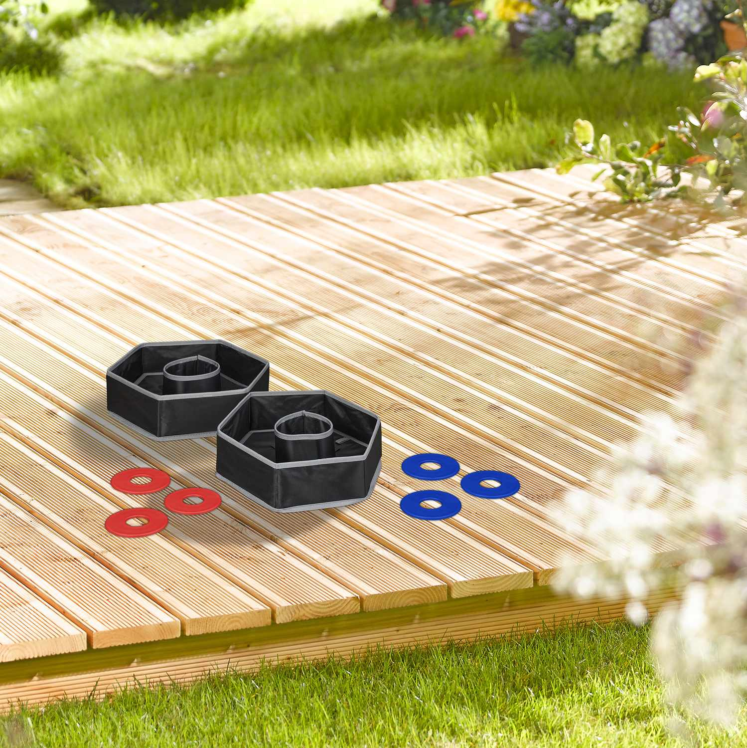 Dos dianas negras de lanzar anillos en una terraza de madera con anillos rojos y azules.