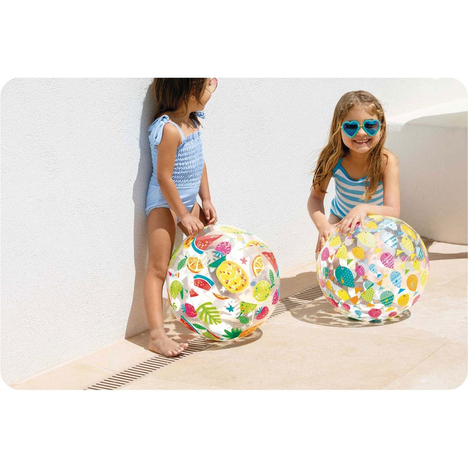 Dos niñas con pelotas inflables coloridas al aire libre.