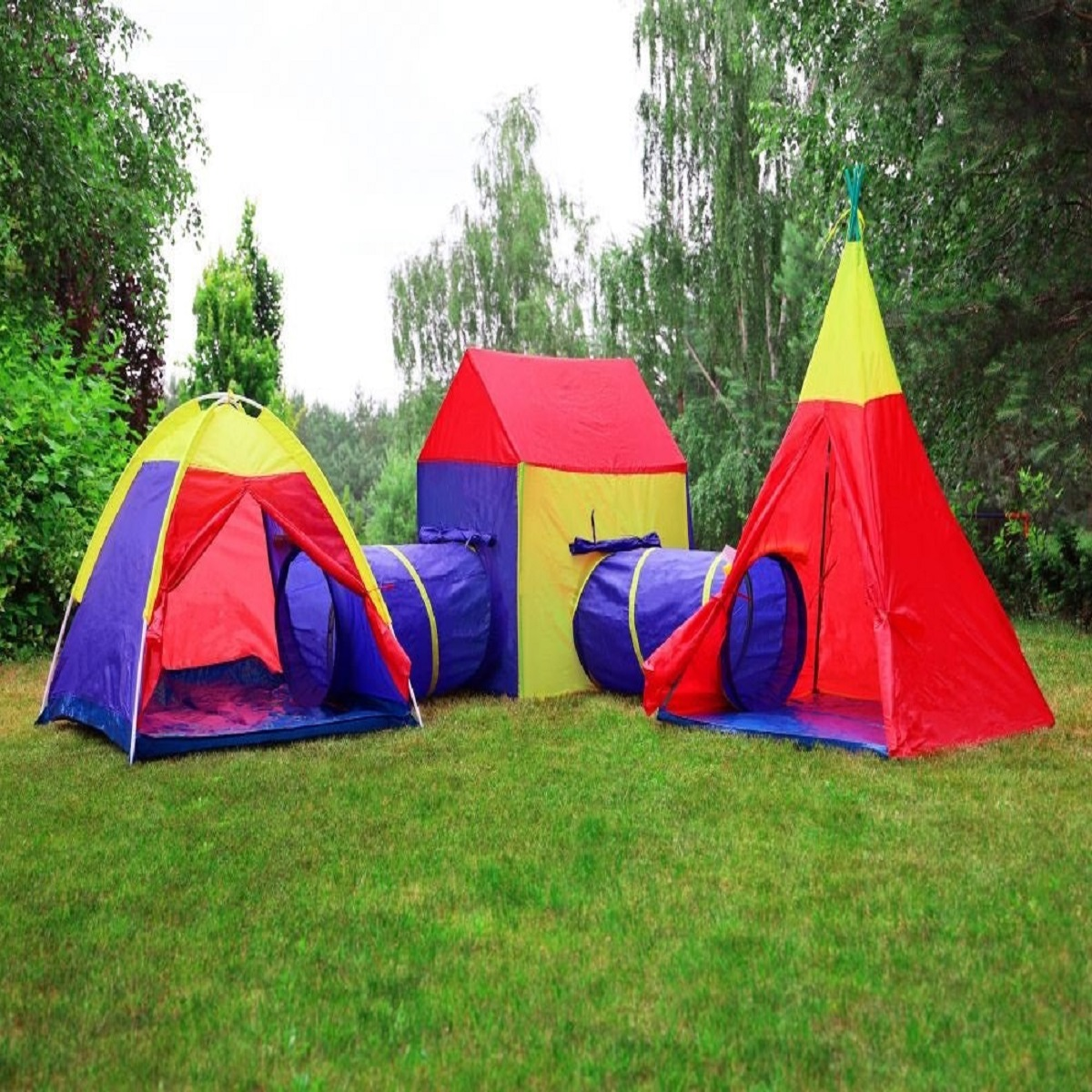 Coloridos juegos de carpas y túneles sobre césped verde, árboles al fondo.
