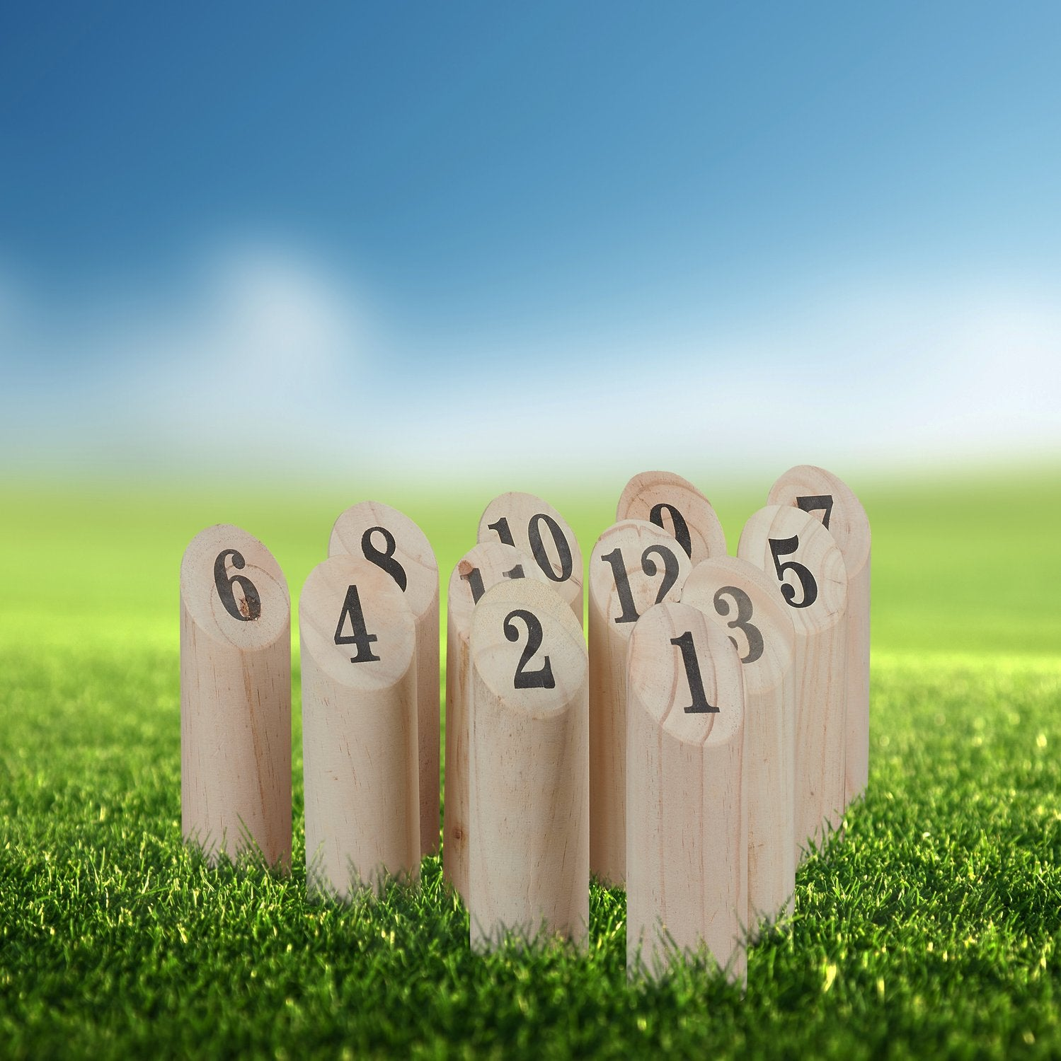 Bloques de madera numerados sobre césped verde bajo cielo azul.