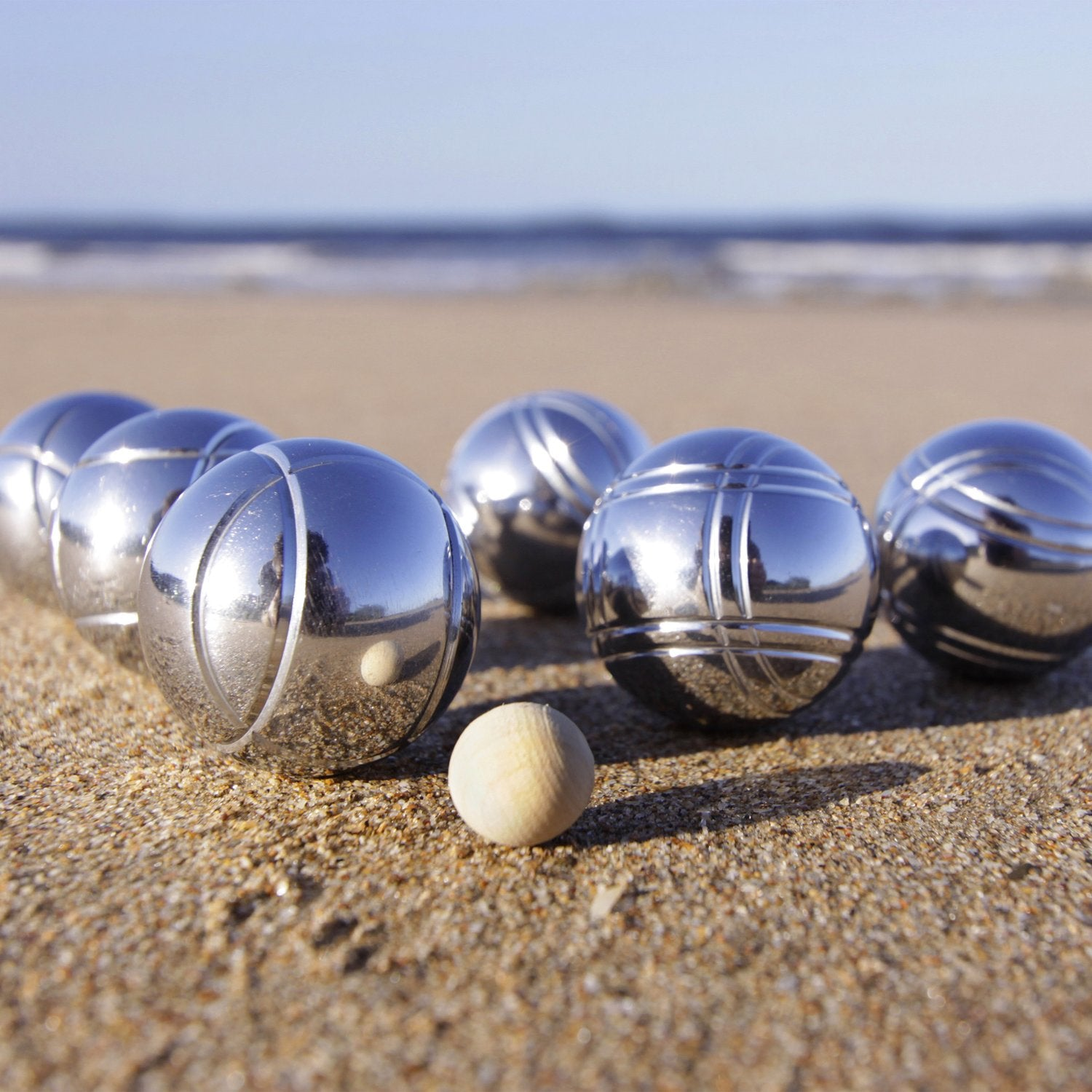 Bolas de petanca y un pequeño objetivo de madera en la arena de la playa.