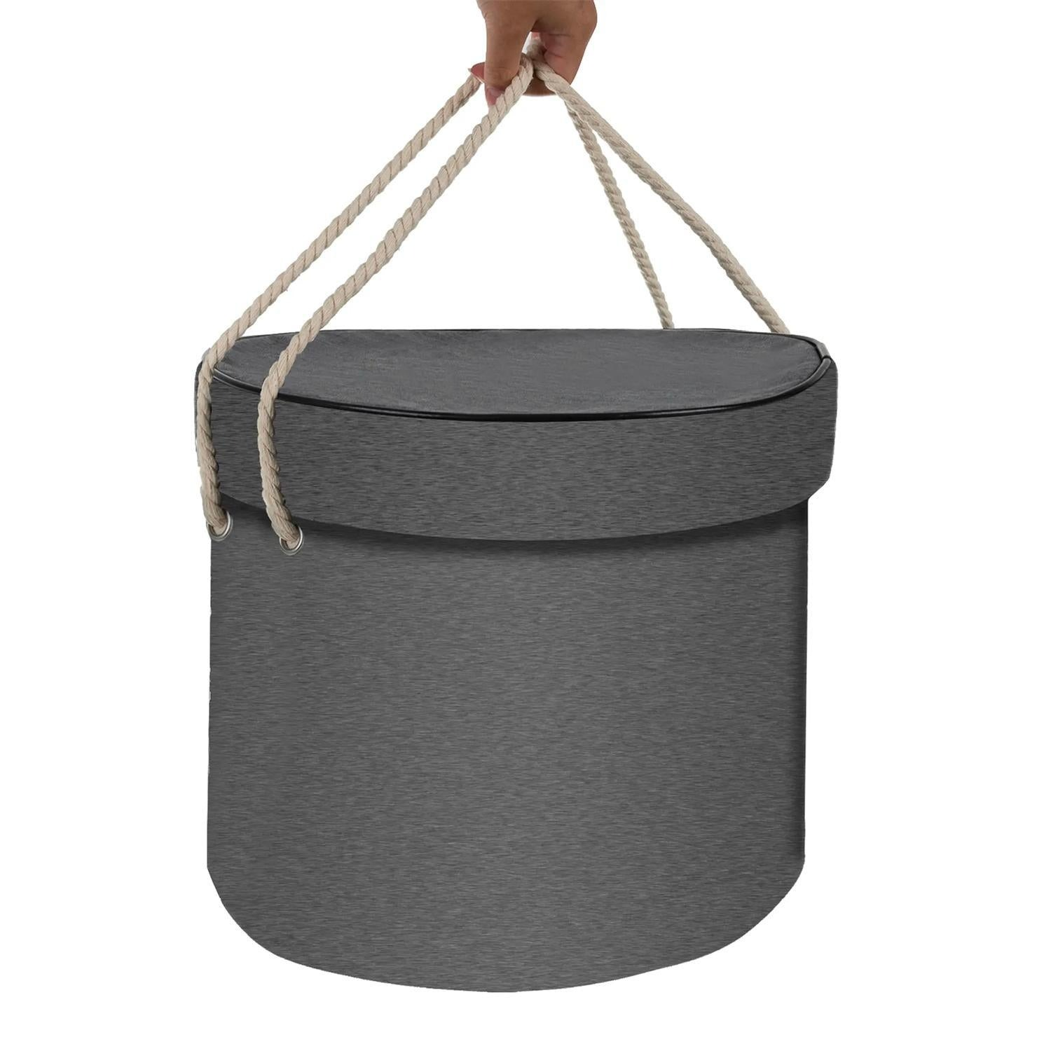 Cesta ovalada gris con asas de cuerda, sostenida por una mano.