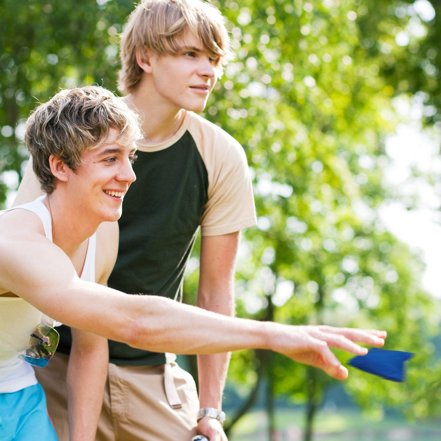 Dos hombres jóvenes juegan al aire libre con un saquito de arena.