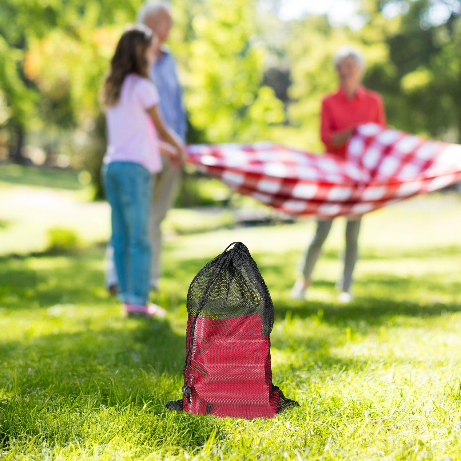 Bolsa roja al frente, familia extendiendo manta de picnic.