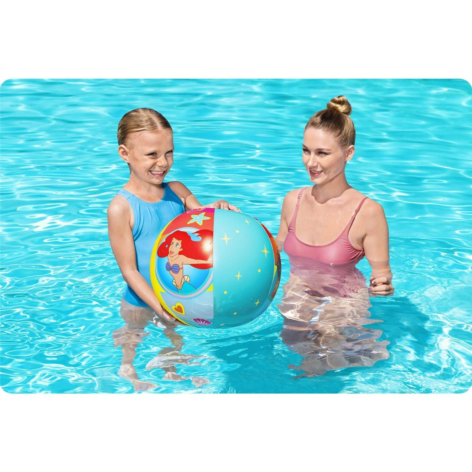 Una niña y una mujer están en una piscina sosteniendo una pelota con Ariel.