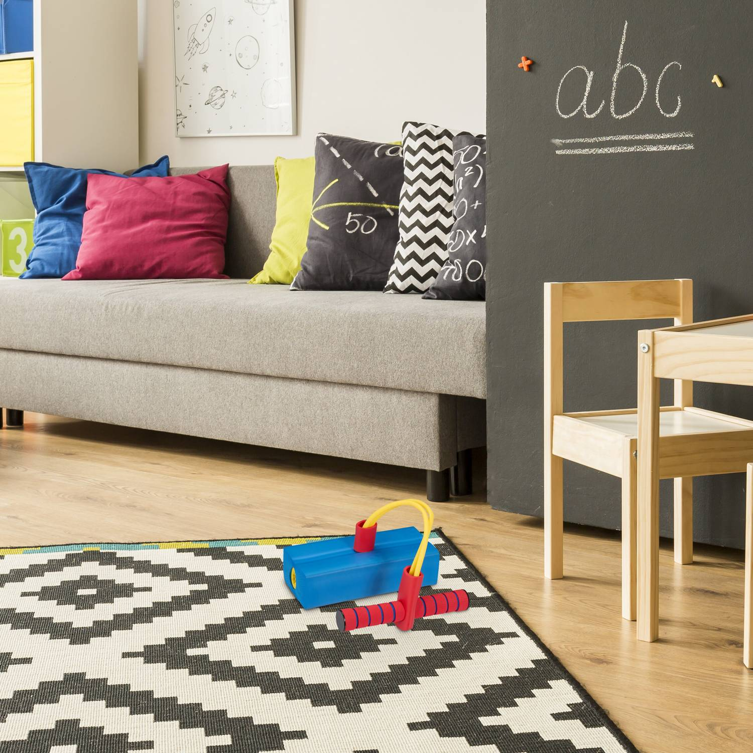 Habitación infantil con sofá, alfombra, juguetes y pizarra.
