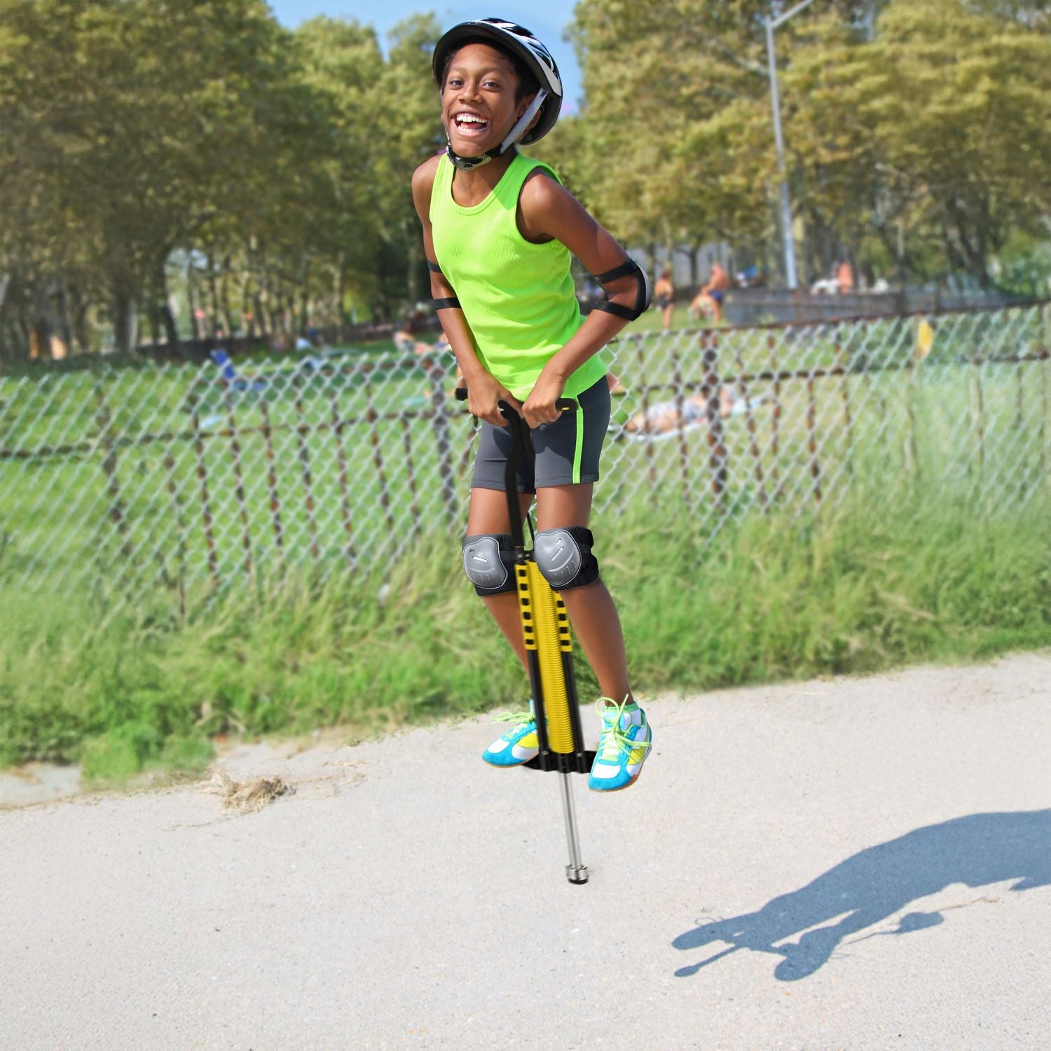 Un niño con equipo de protección salta alegremente en un pogo stick al aire libre.