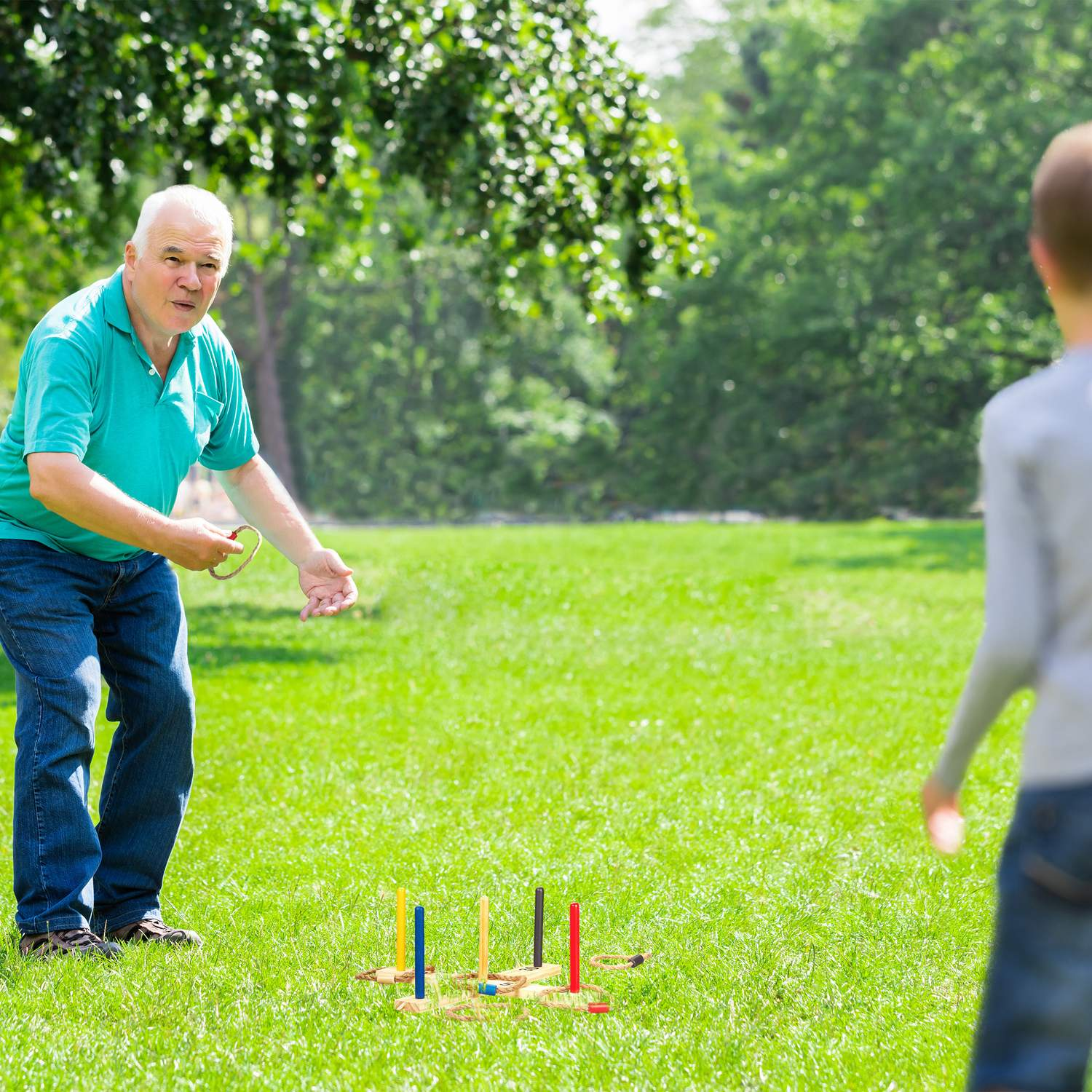 Un hombre lanza un aro a un poste de juego al aire libre.