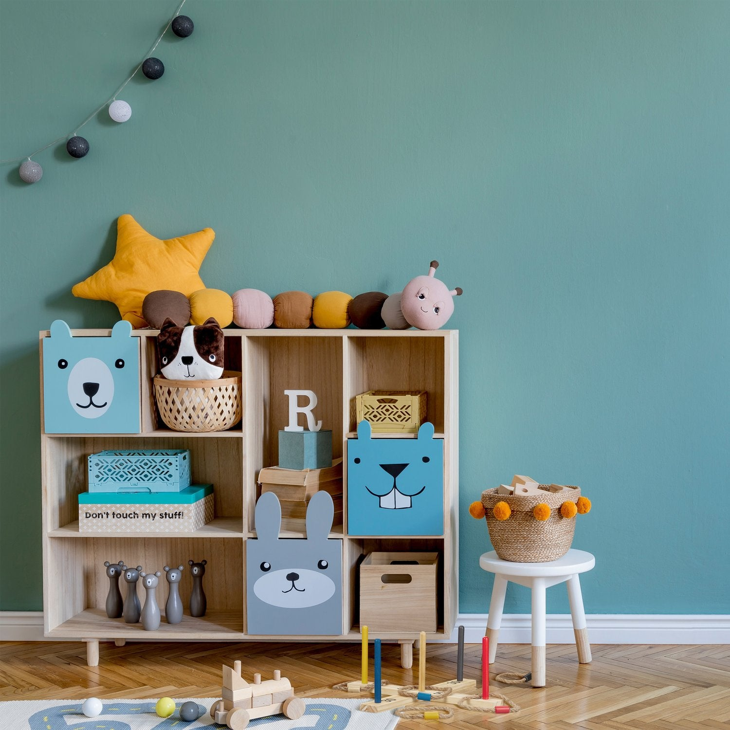 Una habitación infantil con una estantería llena de juguetes, un cojín de estrella y una guirnalda.