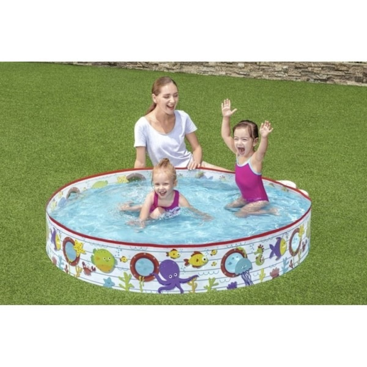 Una mujer supervisa a dos niñas pequeñas en una piscina inflable en el césped.