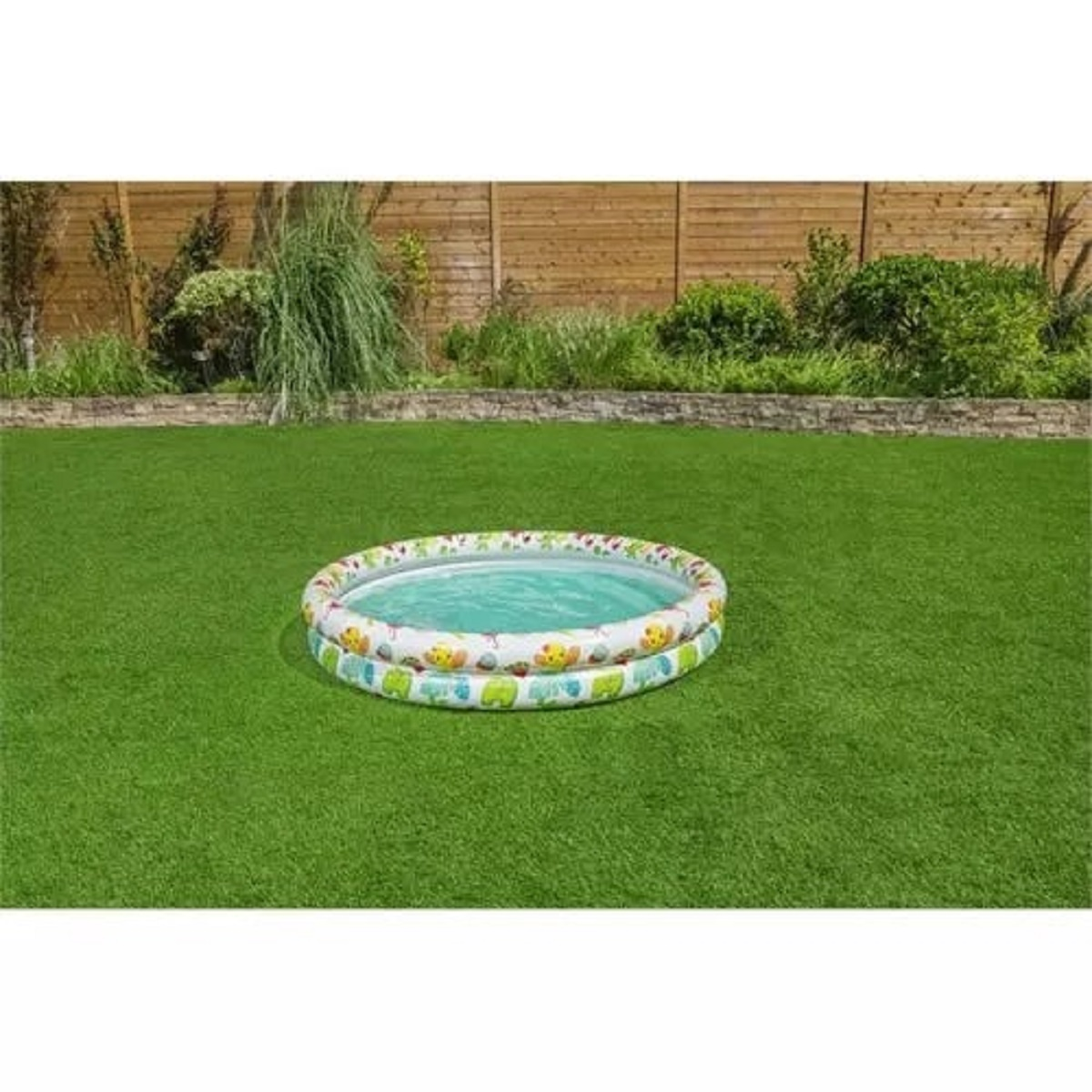 Una piscina inflable con estampado de animales sobre césped artificial verde en un patio.