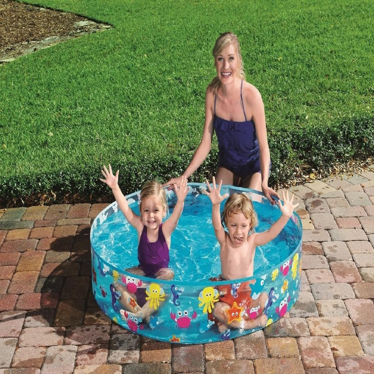 Mujer supervisa a dos niños en piscina inflable decorada con criaturas marinas.