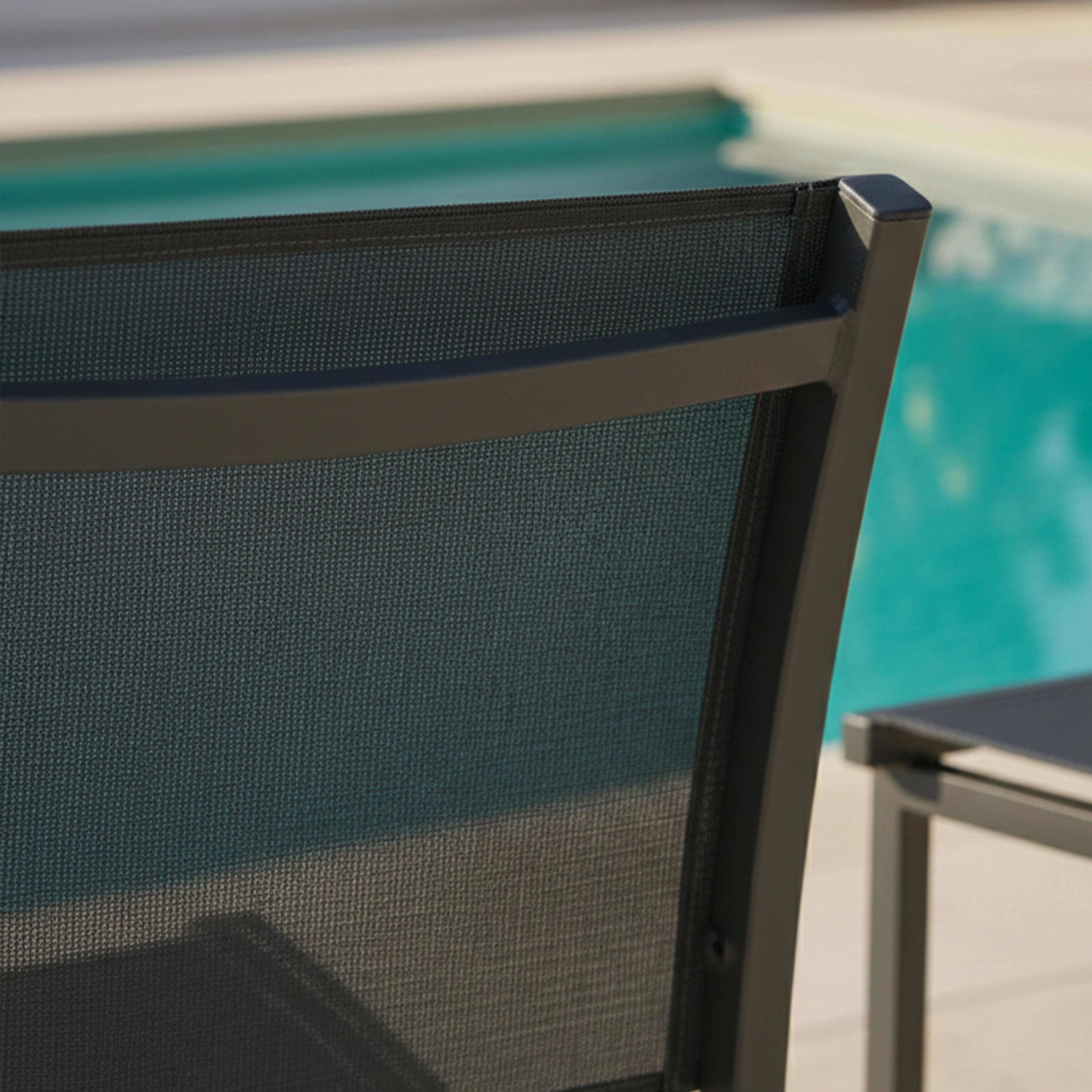 Dunkelgrauer Stoffstuhl mit Metallrahmen neben einem Pool.