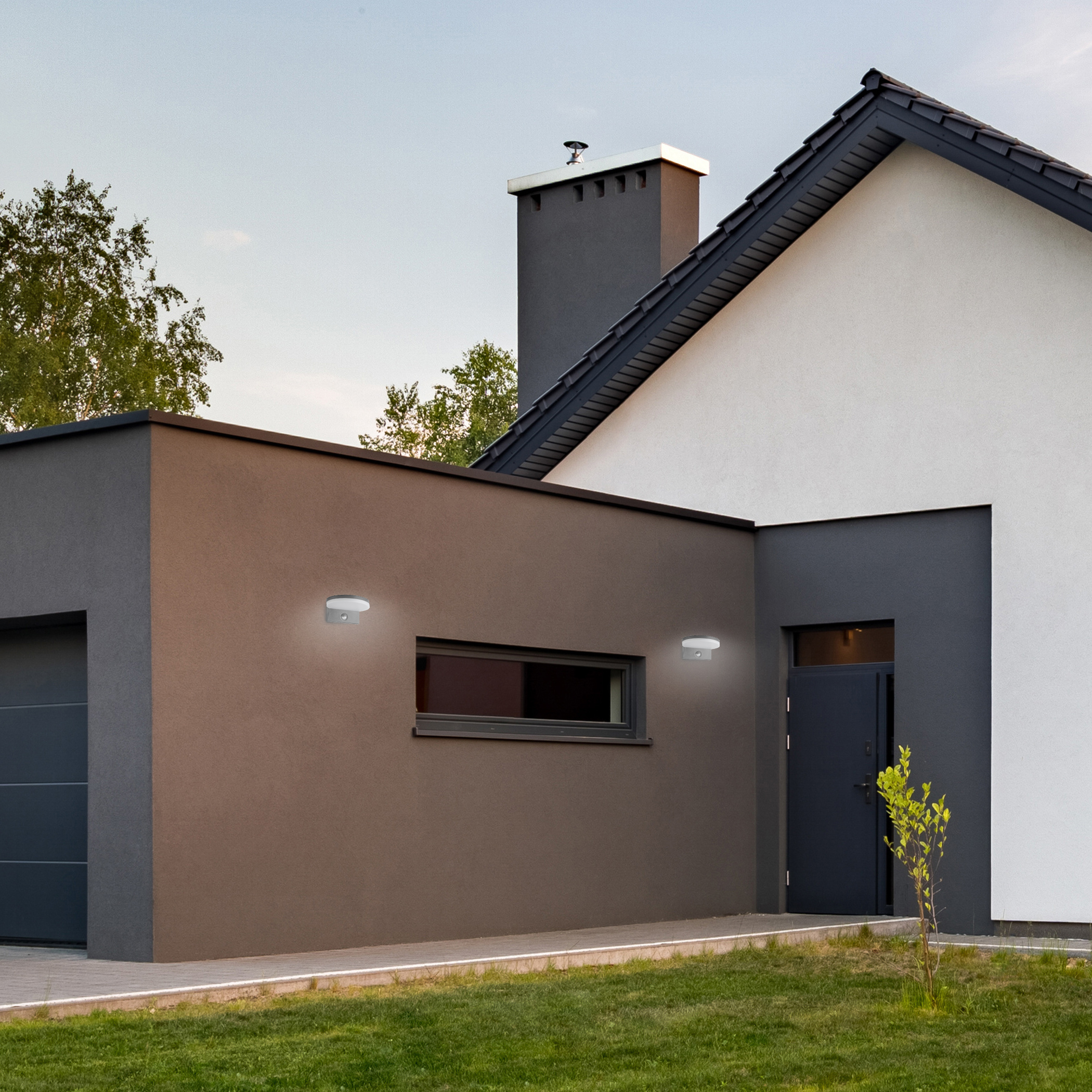 Moderne Hausfassade mit Garage, dunklem Schornstein und Licht.
