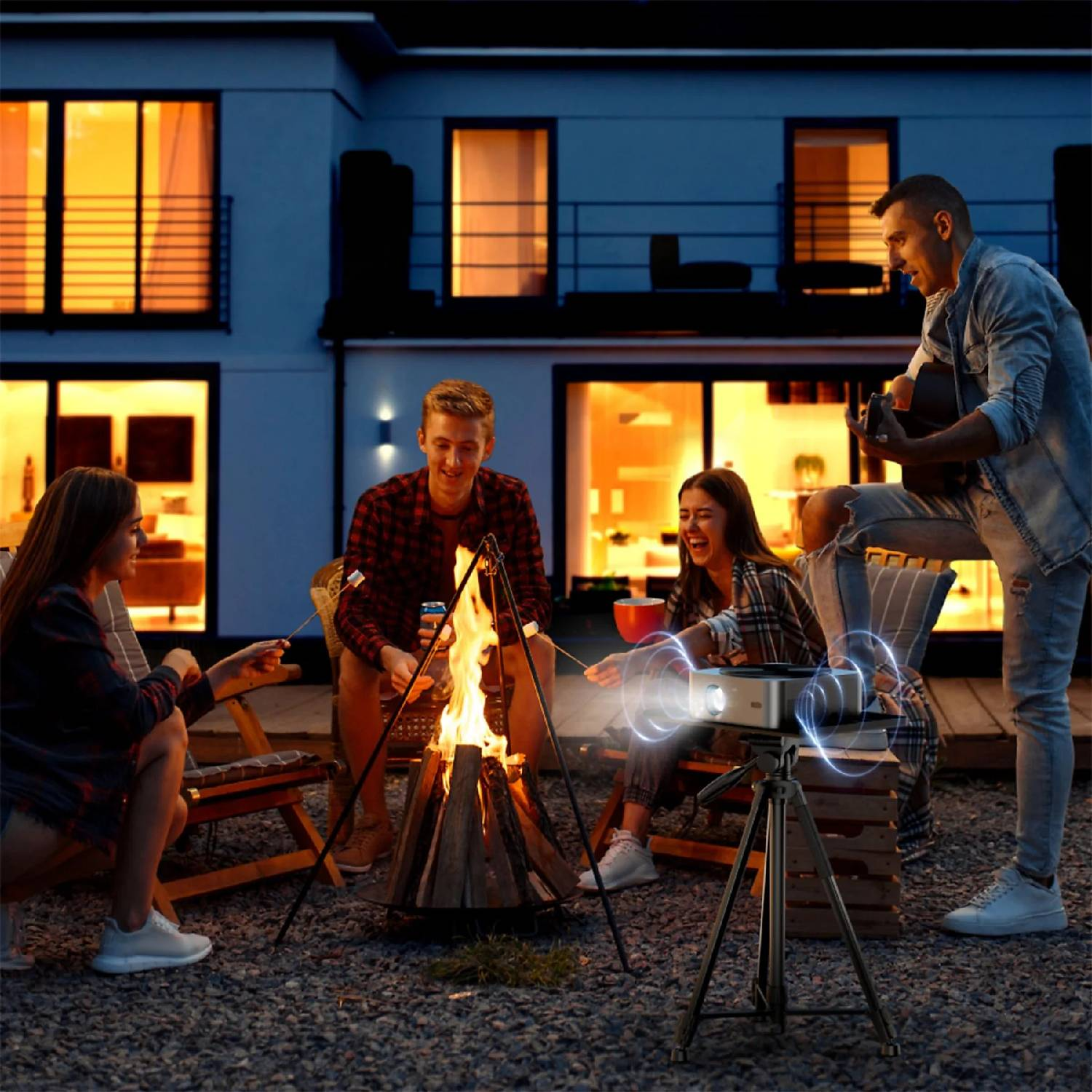 Przyjaciele pieką pianki nad ogniskiem, podczas gdy jeden gra na gitarze.
