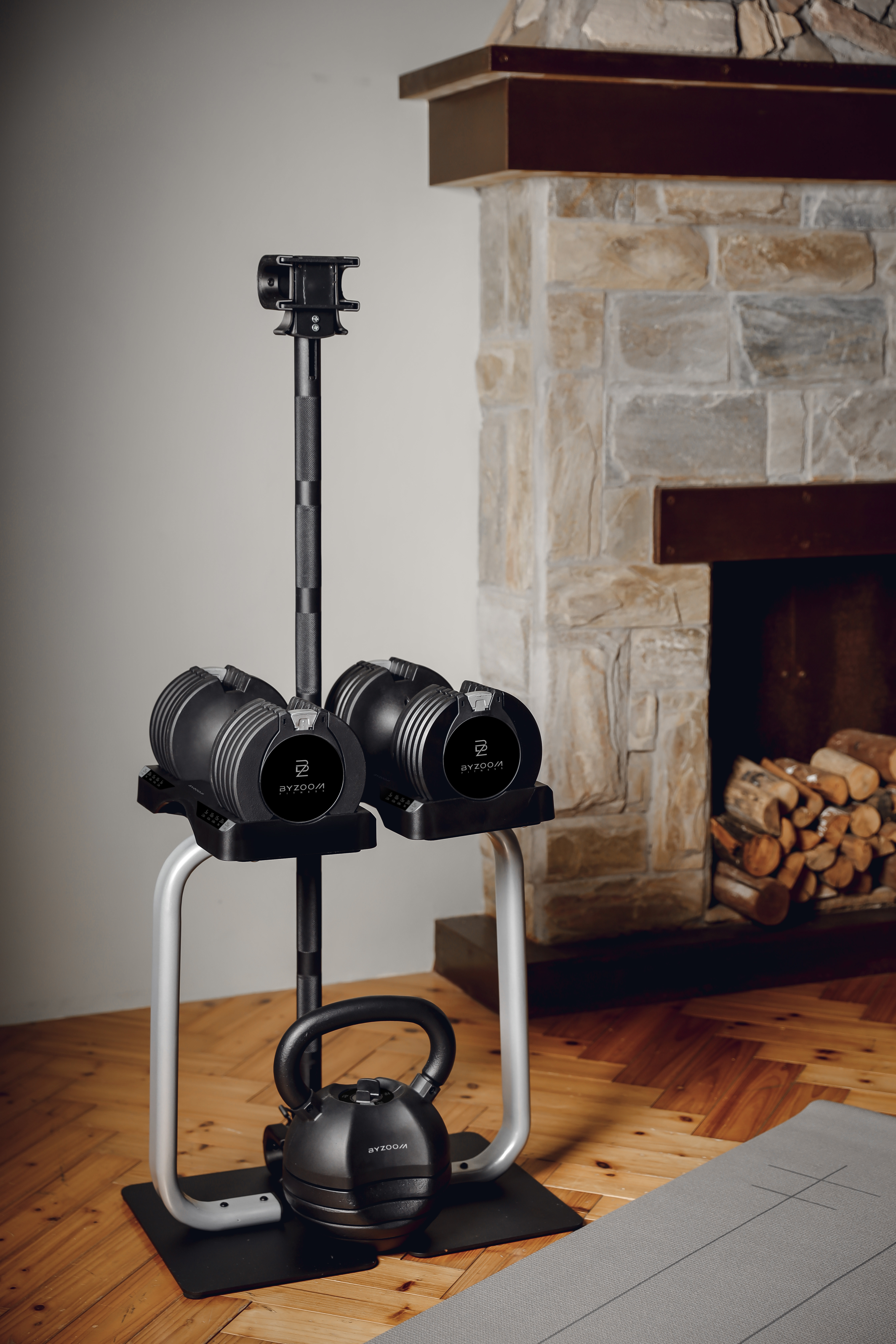 Haltères et kettlebell réglables sur un support devant une cheminée.