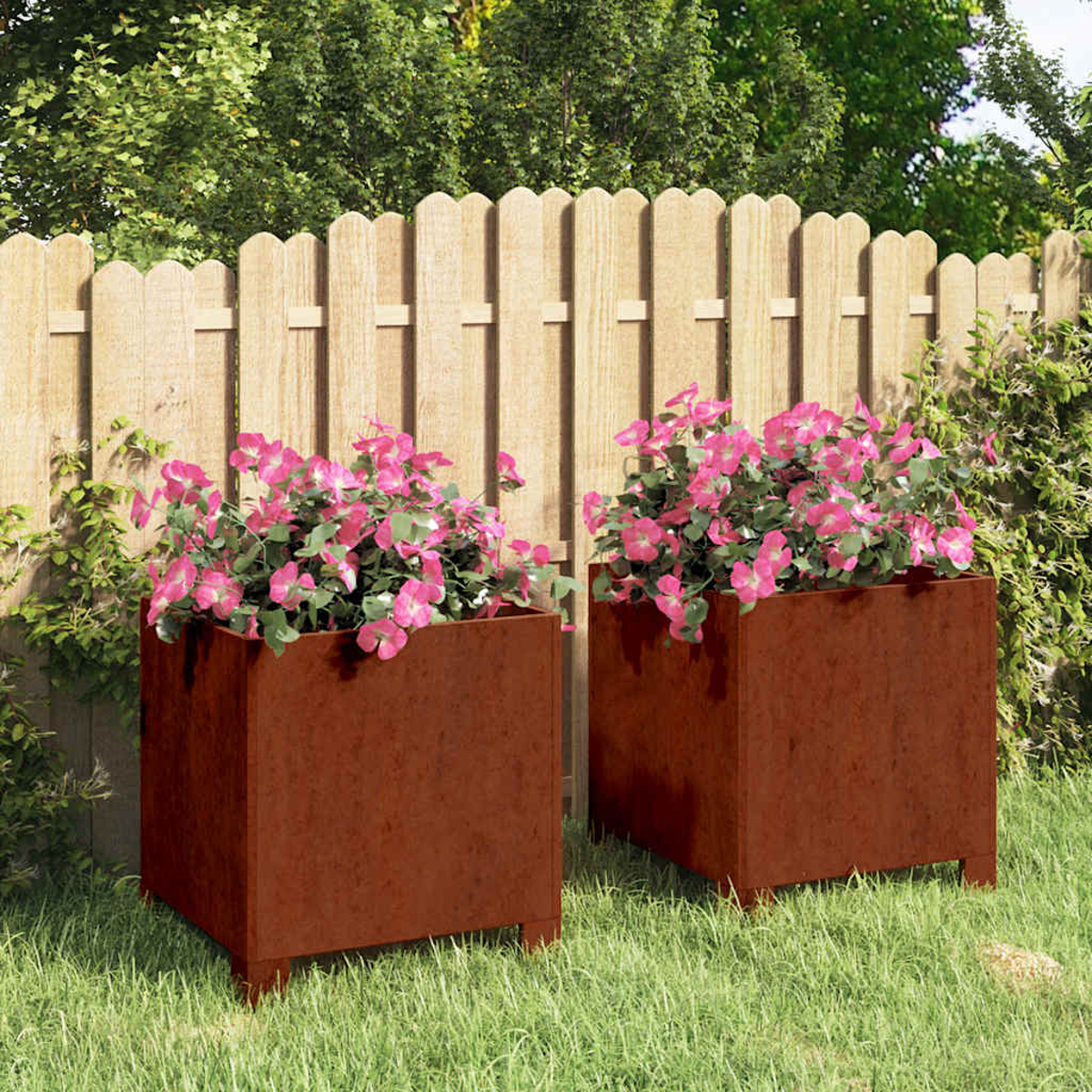 Zwei rostige Metall-Pflanzkästen mit rosa Blumen vor einem Holzzaun.