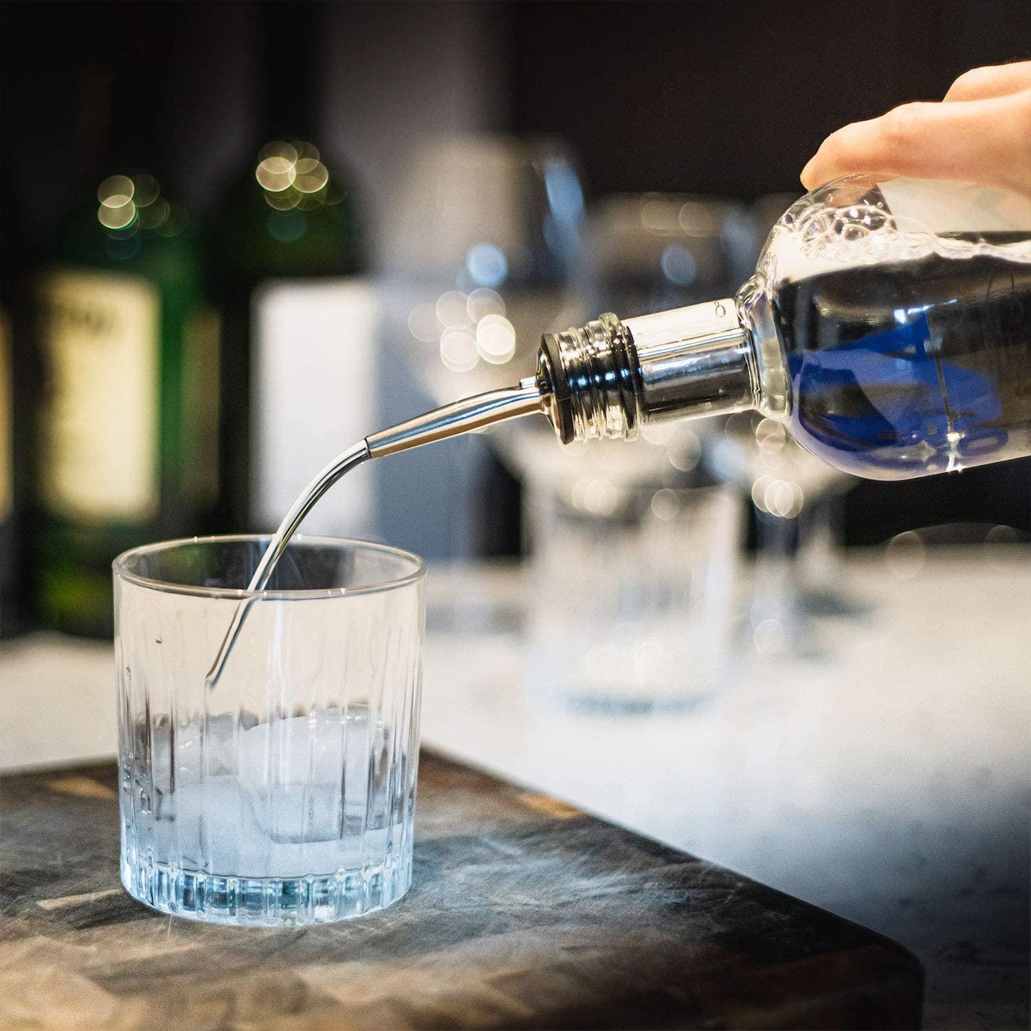Klare Flüssigkeit wird aus einer Flasche in ein Glas mit Eis gegossen.