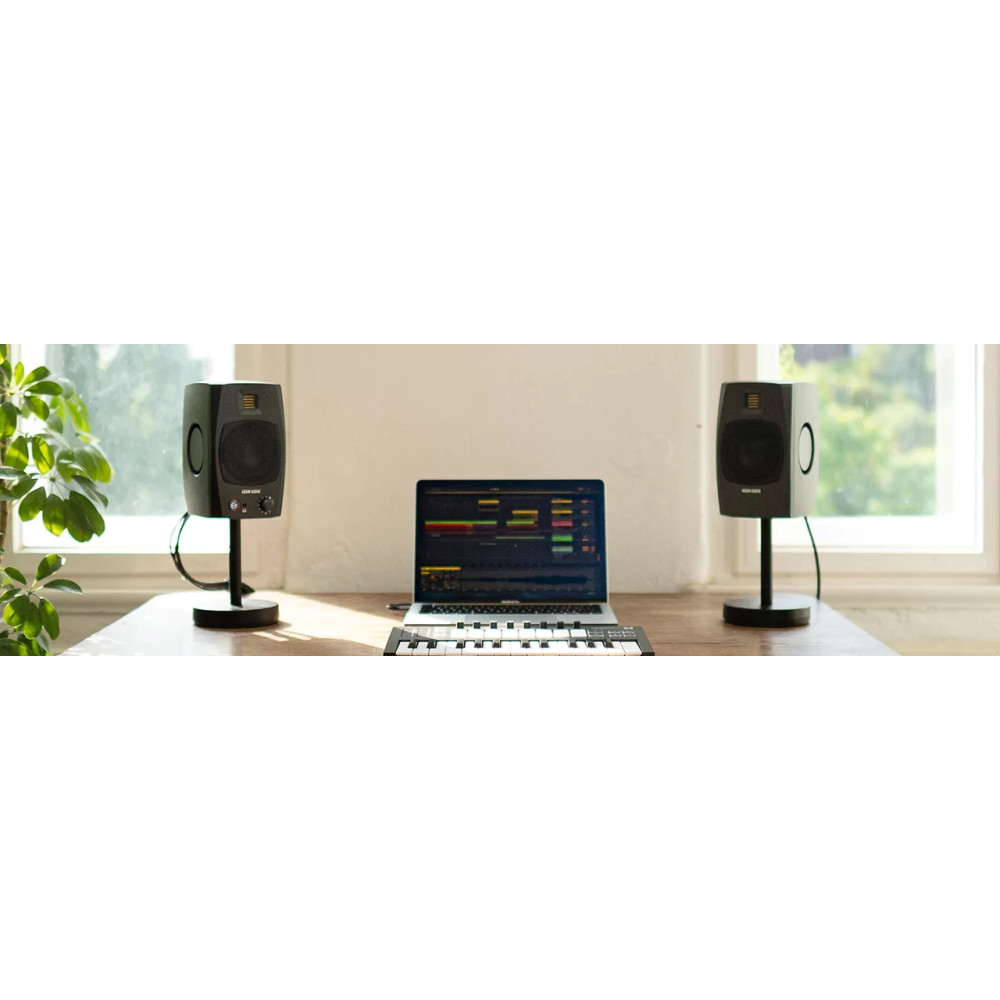 Laptop z oprogramowaniem muzycznym, dwa głośniki i klawiatura na drewnianym stole.