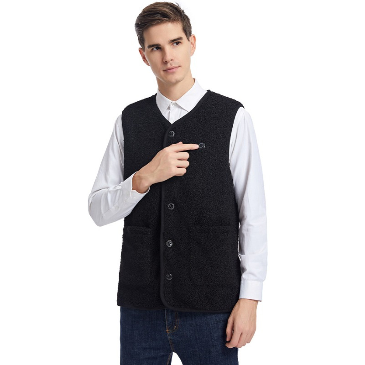 Mężczyzna w czarnej kamizelce na białej koszuli i dżinsach, wskazujący guzik.