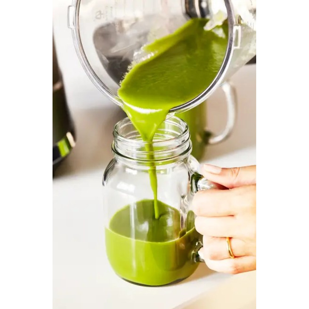 Zielony sok jest przelewany z blendera do szklanki.
