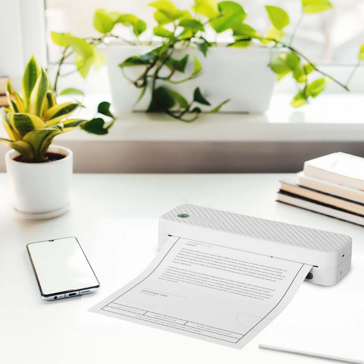Drukarka drukuje dokument, obok smartfon i rośliny.