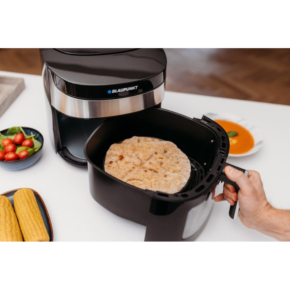 Mężczyzna wyjmuje placek z czarnego kosza frytkownicy beztłuszczowej.