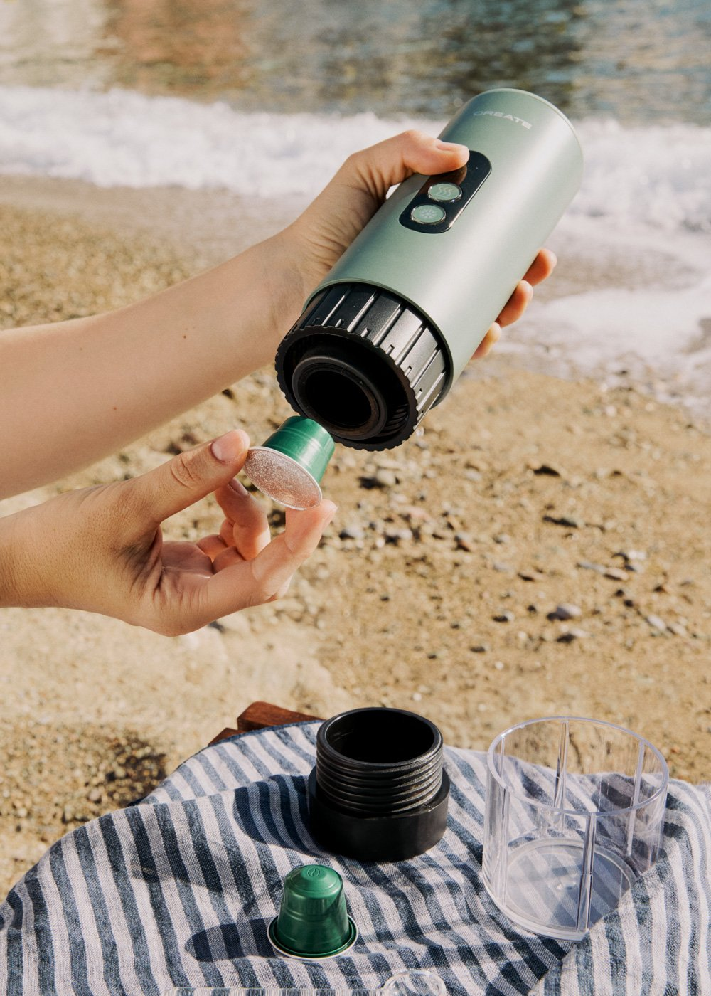 Una persona prepara café en la playa con una cápsula de café.