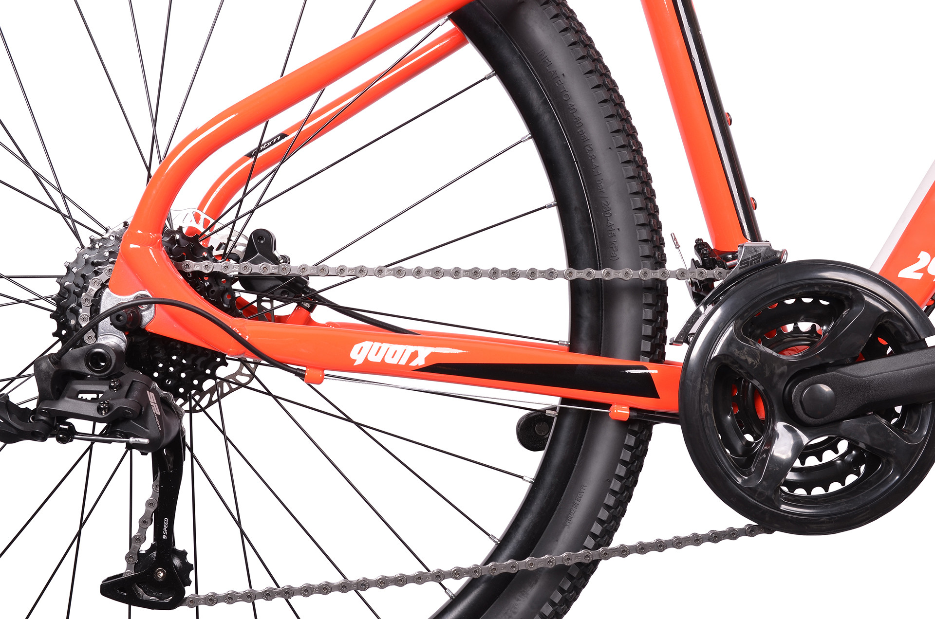 Zbliżenie pomarańczowej ramy roweru z łańcuchem, zębatkami i oponą.