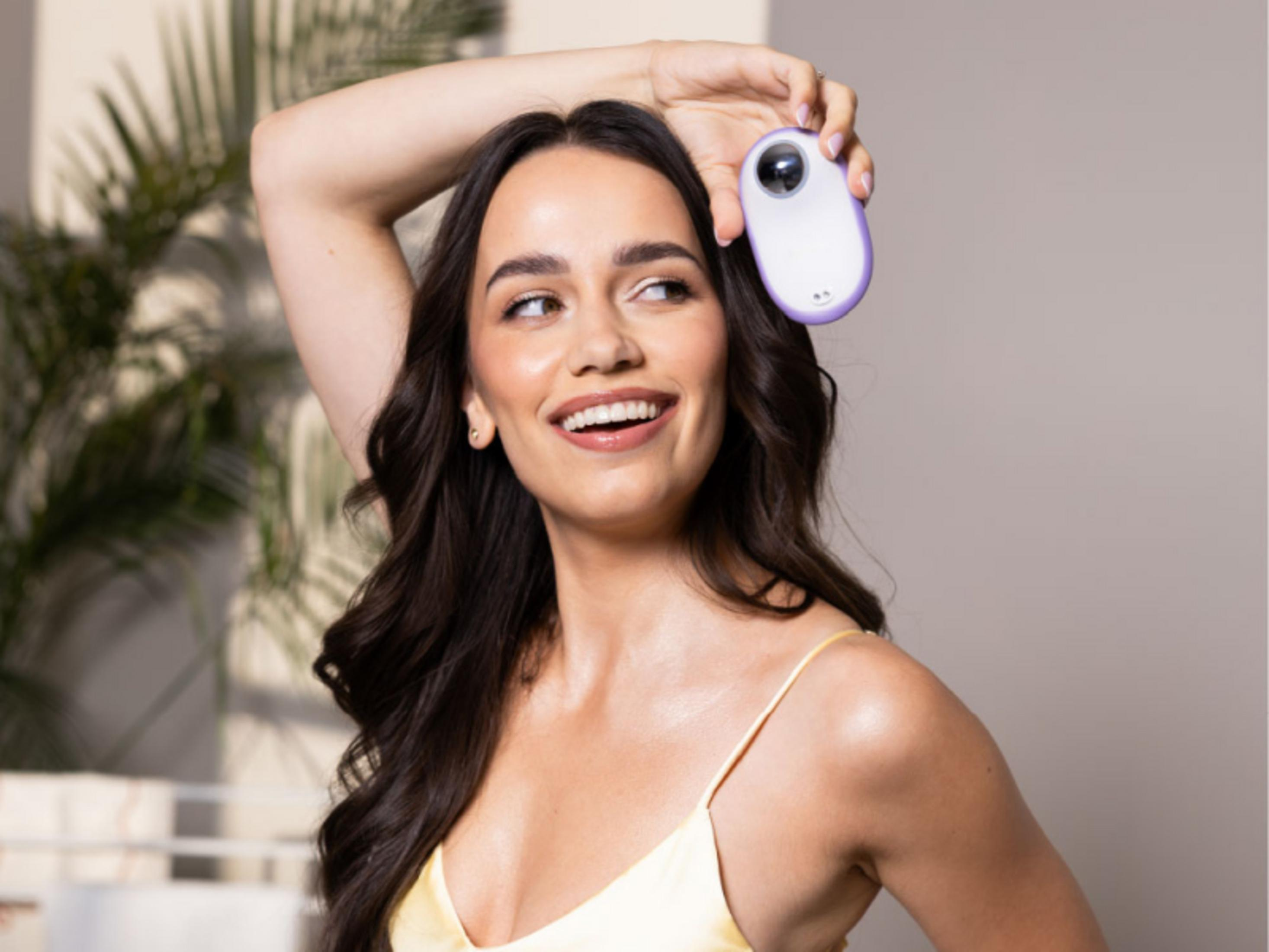 Donna tiene un dispositivo per la cura della pelle viola e bianco sopra la testa.