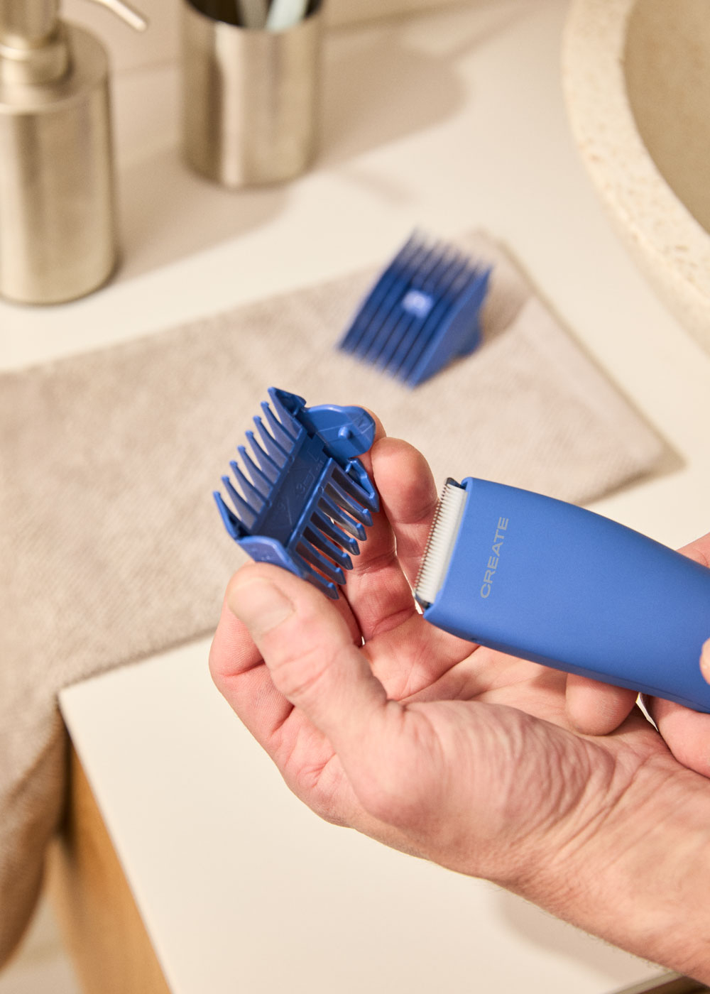 Una mano sostiene un accesorio azul para cortapelos sobre el dispositivo.