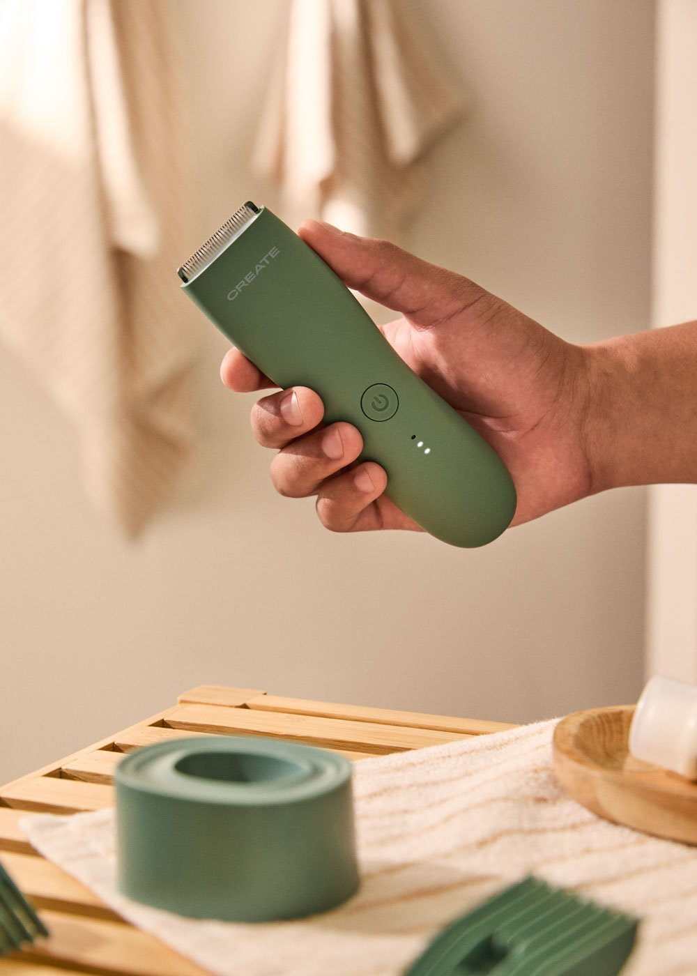 Una mano sostiene una recortadora verde con un símbolo de encendido.
