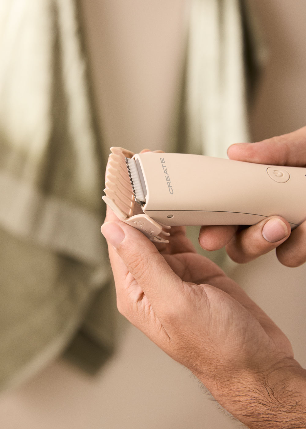Manos sosteniendo una cortapelos beige con un accesorio.