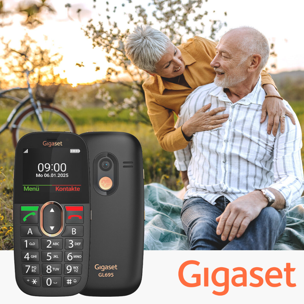 Ein Gigaset-Handy liegt vorn. Ein älteres Paar lächelt sich im Hintergrund an.